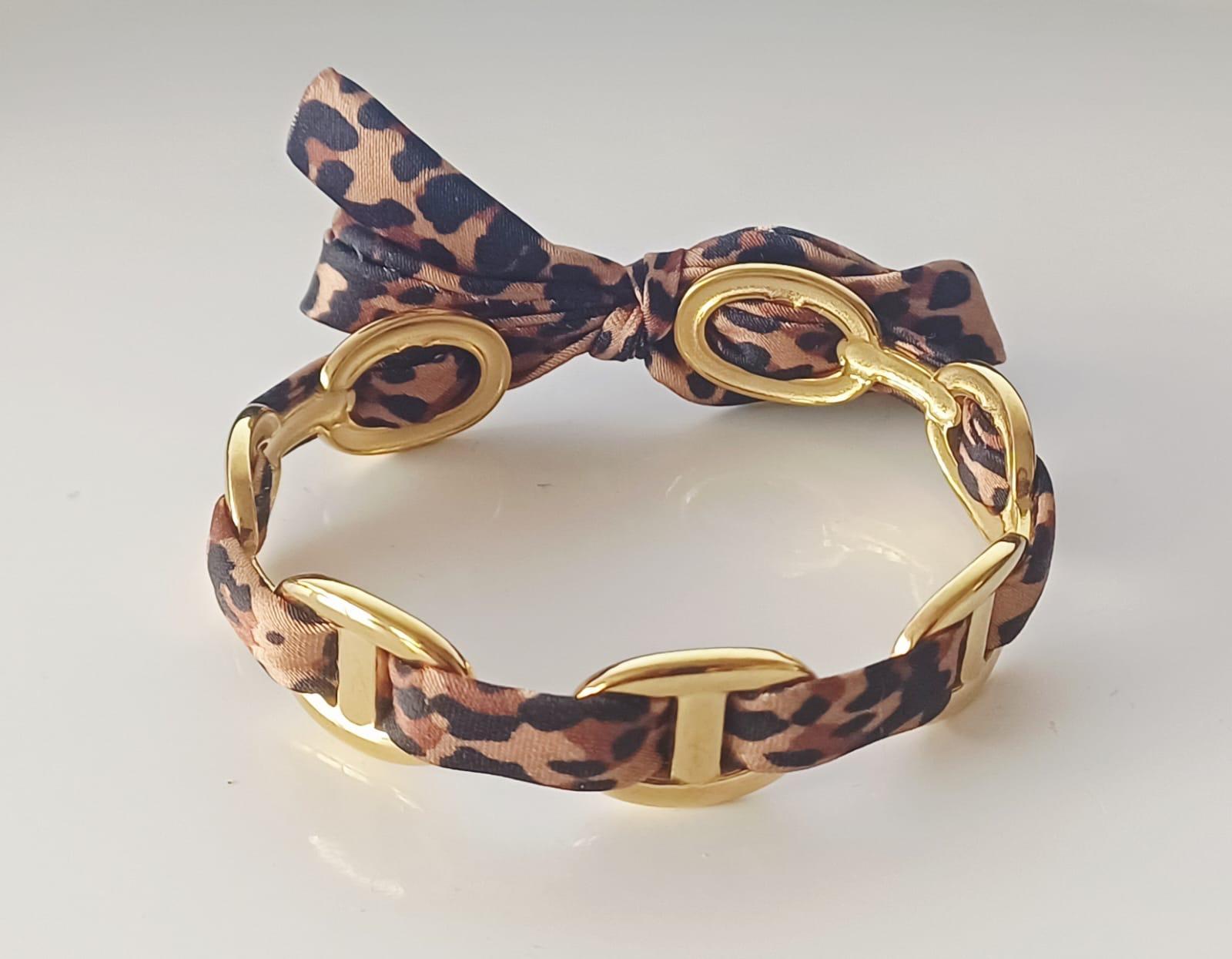 Bracelet manchette doré avec ruban imprimé léopard et nœud décoratif.